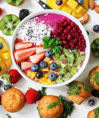 witte achtergrond met verschillende soorten fruit soorten met in het midden een schaal yoghurt met fruit erin