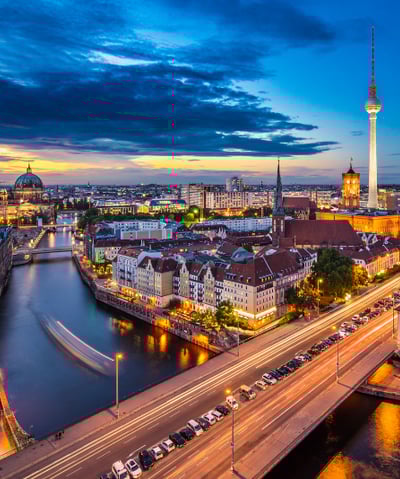 a cityscape of a river with a bridge and a tower