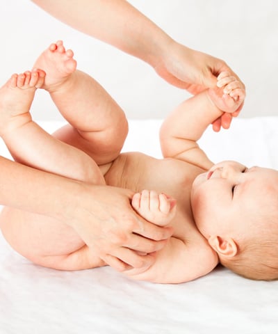 a baby is laying on a bed with a woman's hands