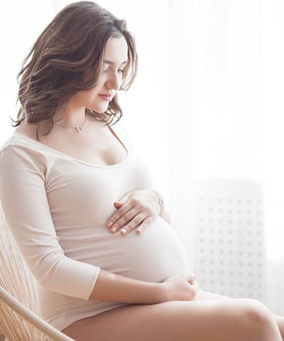 a pregnant woman sitting in a chair holding her belly