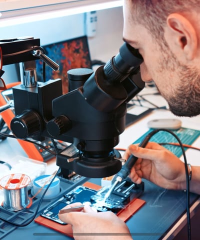 a man in a black shirt is looking at a microscope