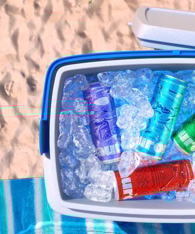 Cerveja Aurora em 3D, lata vermelha em cooler com gelo, ambiente de praia.