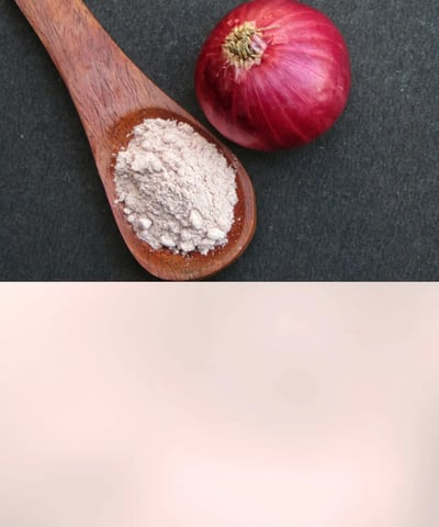 Fine white onion powder in a glass jar next to raw onions