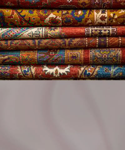 Traditional handwoven carpets with intricate patterns displayed on a showroom floor