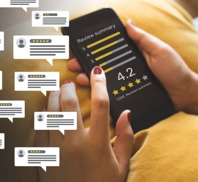 Person monitoring and managing online reviews and customer feedback on a mobile phone.