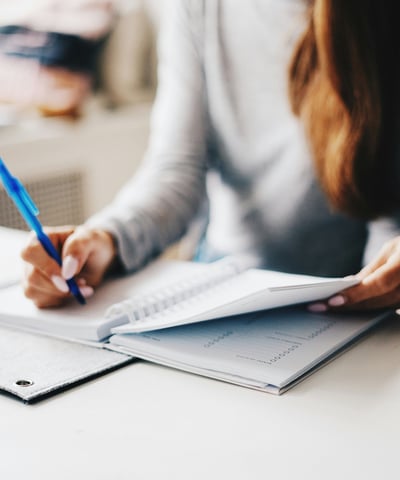 Woman is writing something on a notebook