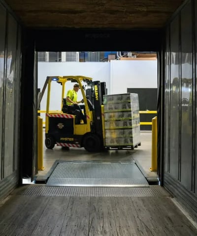 Forklift operator loading pallet into truck at warehouse — efficient delivery and logistics handling