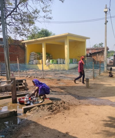 Woman washing utensils front of chabutra