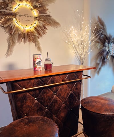 Eine braune Bar, auf der ein roter Smoothie steht, an der Wand hängt ein rundes Schild mit dem LOGO