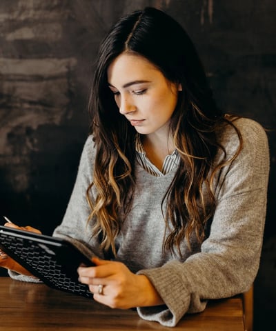 a woman sitting at a table with a laptop and a tablet