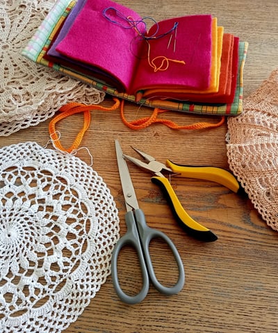 Napperon au crochet posé sur une table des ciseaux une pince des aiguilles à coudre dans un étui