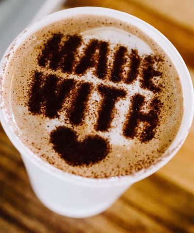 Latte art heart with “made with love” message on a coffee cup