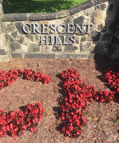 Crescent Hills stonework sign and red flowers spelling C H