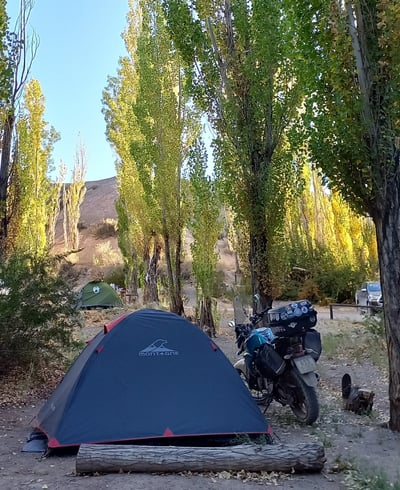 a motorcycle parked in a wooded area with a tent