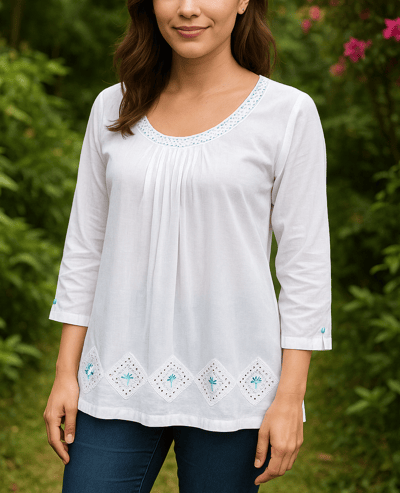 a woman in a white shirt and jeans standing in front of a bush