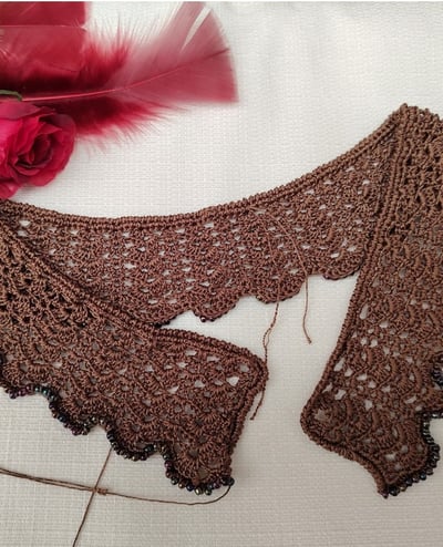 Collier au crochet dans un fil de soie marron dans un point fantaisie sur le haut gauche des plumes