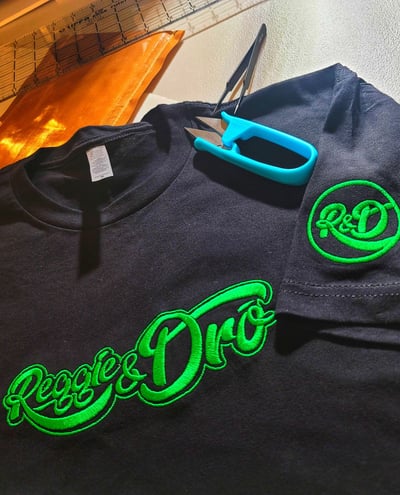 Black custom embroidered shirt with green Reggie & Don logo design – personalized embroidery by Stit