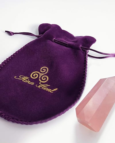 a purple velvet pouch bag with a crystal point of pink quartz