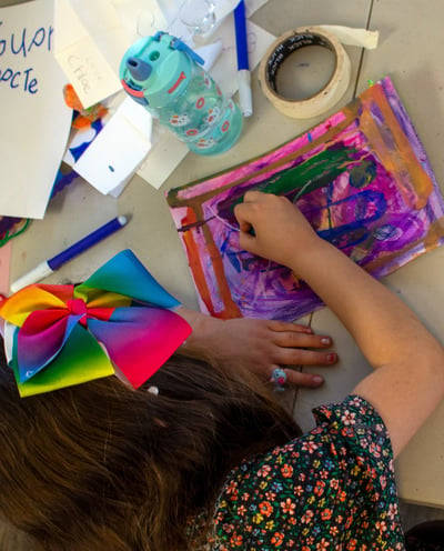 Young child using pastels to create a colorful piece of art on paper.