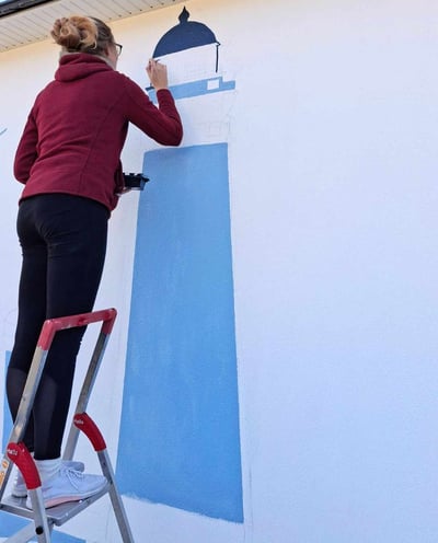 Artiste en train de peindre une fresque bleue sur un mur de maison 