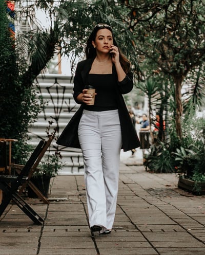 uma mulher caminhando pela calçada com uma xícara de café