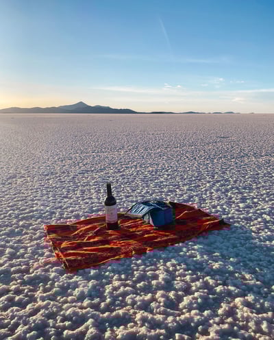 A towel and a bottle of wine set up during sunset on the Uyuni Salt Flat.