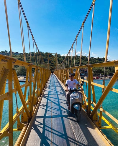Photo of a local crossing the Yellow Bridge connecting Nusa Ceningan to Nusa Lembongan on a scooter.