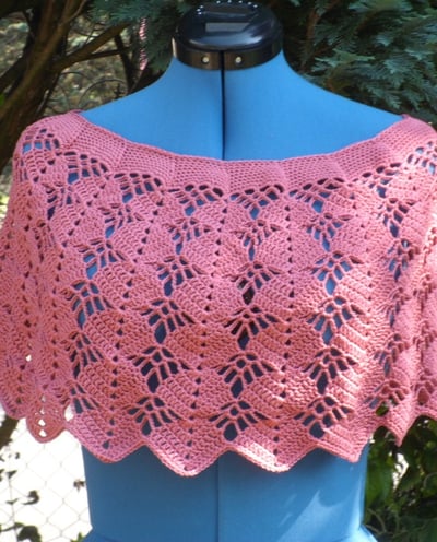 cache épaule crocheté dans un fil coton couleur vieux rose posé sur un mannequin de couleur bleu  