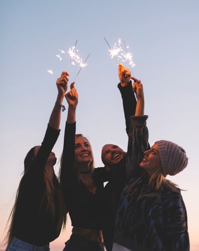 a group of friends holding sparklers in the sky