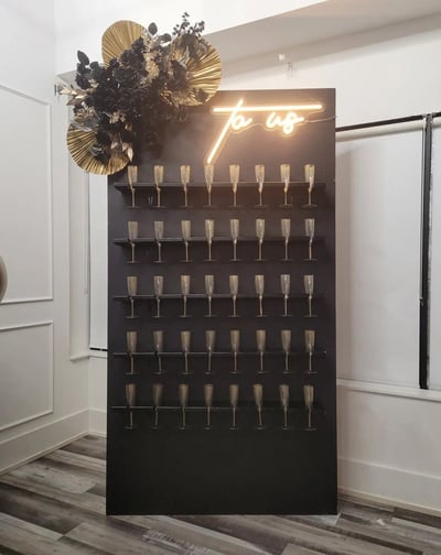 Black champagne with a floral arrangement and champagne flutes