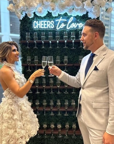 a man and woman holding champagne flutes in front of a sign that says cheers to love