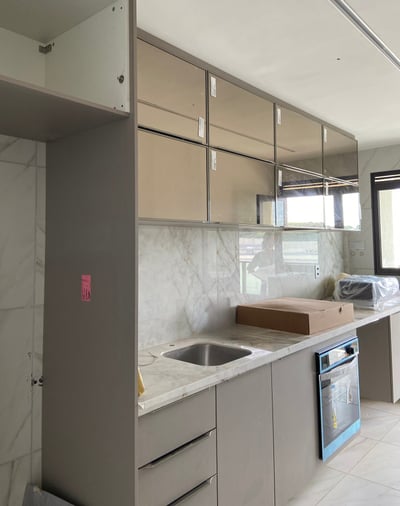 Cozinha em reforma pela Nattú Engenharia com armário planejado, bancada de mármore e eletrodoméstico