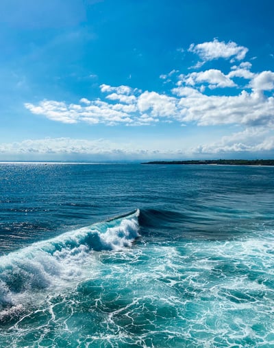 A wave perfectly curling and breaking along the rocky point of Nusa Ceningan.