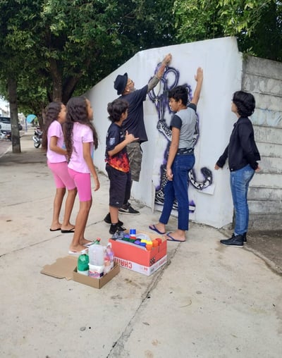 Jovem aplicando stencil – Estudante pratica a aplicação de stencil em uma parede da escola.