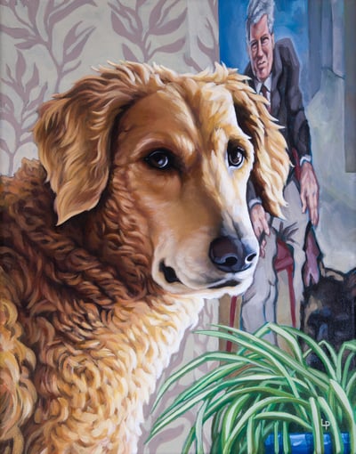 A curly-coated golden doodle dog turns toward the viewer, before a plant and a painting of a man.