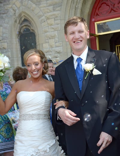 a bride and groom are walking our from the church and bubbles around them