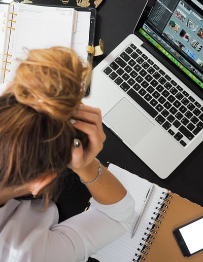 a woman sitting at a desk with a laptop and a notebook