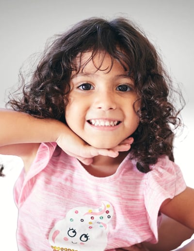 young girl with a big smile and curly, dark hair