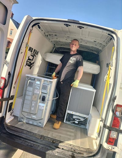 man stading next to washing machine in the back of van