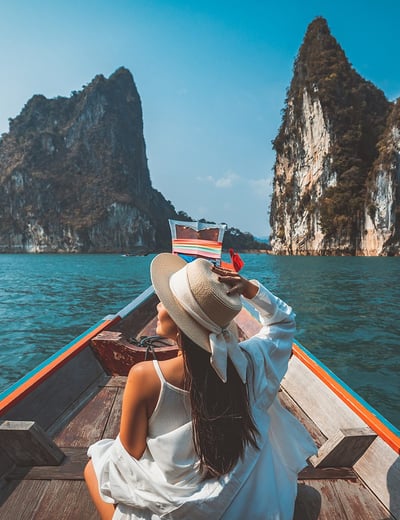 girl solo travelling on a boat overlooking Thailand landscape