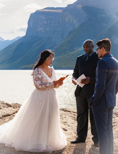 Bride and groom sawing vows in front of a mountain during their Banff elopement