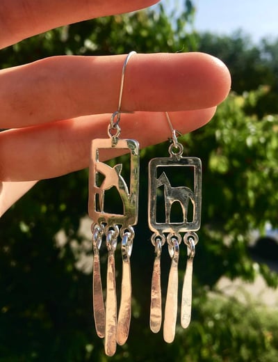 a pair of earrings with a horse and a swallow on it