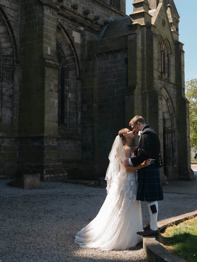 a bride and groom kissing in front of a church