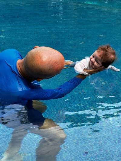 a man holding a baby in a pool