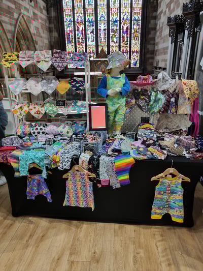 a table with a display of baby clothes and childrens clothing made by Distinctly individual