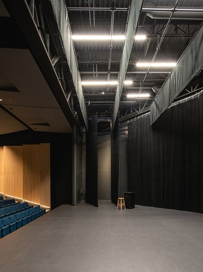 a large empty auditorium with blue seats and a wooden floor