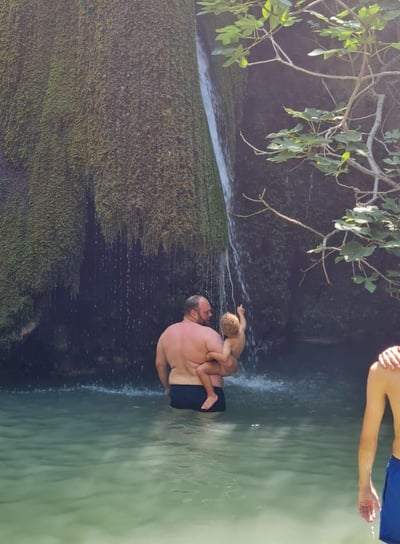 Vater und Sohn baden am Wasserfall