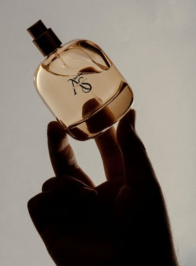 a person holding a bottle of perfume our designer perfumes are here at attarsouq