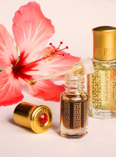 a bottle of perfume with a flower in the background explore  our attars at attarsouq