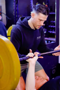 A personal trainer assisting his client perform a bench press exercise